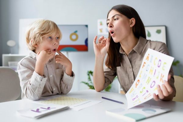 Afasia - niño en la consulta de la logopeda aprendiendo de nuevo a hablar correctamente