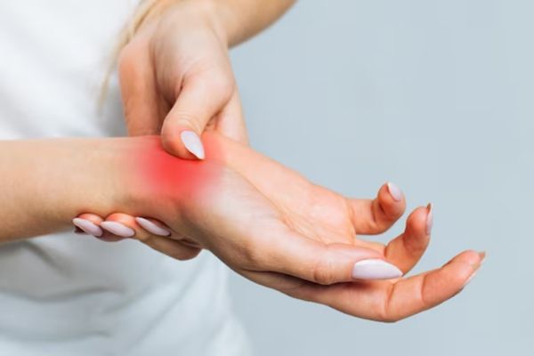 Lupus - primer plano de las manos de una mujer, cogiendo con una mano la muñeca de la otra que se encuentra dolorida