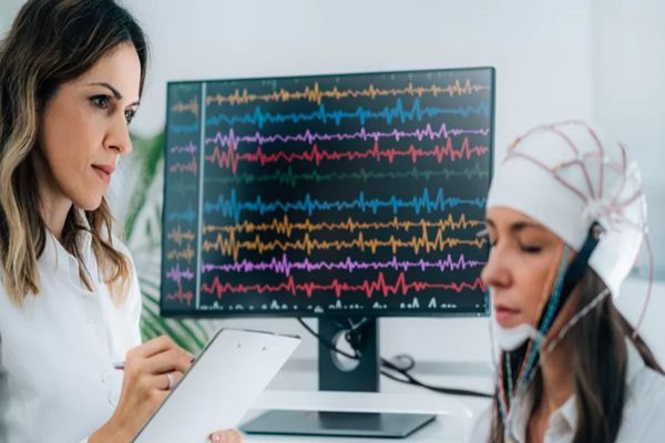 joven sometiéndose a un tratamiento de estimulación cerebral bajo la atenta mirada de la especialista