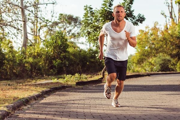 dermatitis seborreica - hombre blanco sudoroso con una camiseta blanca y unos shorts azules corriendo por un parque