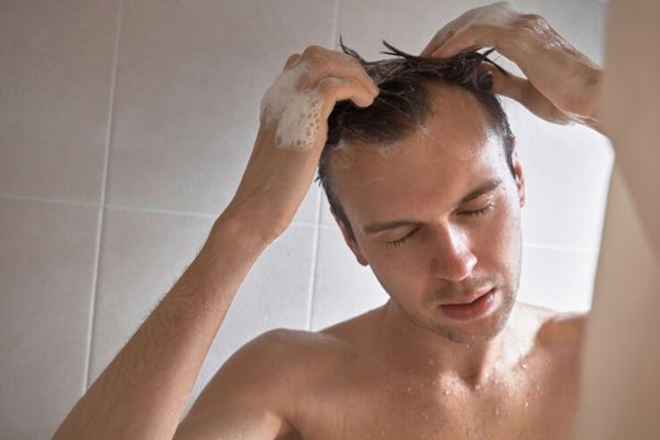 dermatitis seborreica - hombre blanco aplicándose champú en la ducha