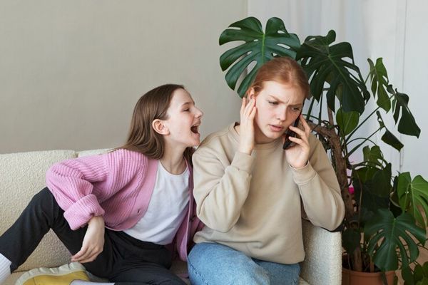 TDAH - Madre estresada al no poder hablar tranquilamente por teléfono debido a que su hija la interrumpe constantemente, motivado al trastorno de impulsividad que sufre