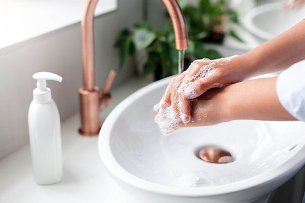 mujer lavándose la manos con jabón en el cuarto de baño