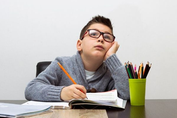 TDAH - Niño distraído durante las horas de estudio, motivado al trastorno de déficit de atención que padece
