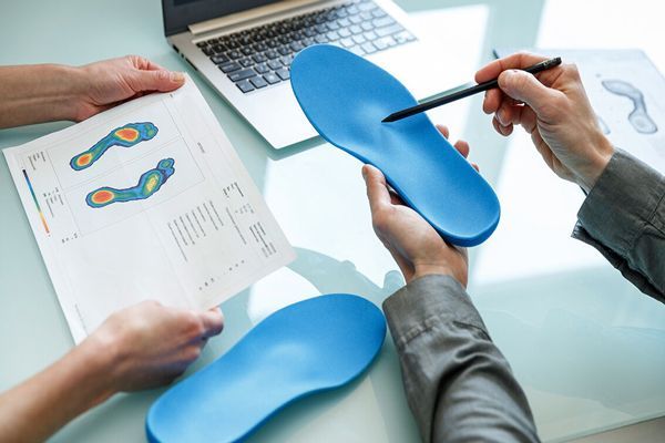 hombre en la consulta del podólogo revisando las plantillas a usar para tratar este problema con la planta de los pies