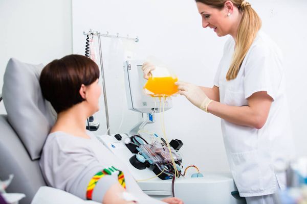 mujer en el hospital hablando con una enfermera mientras se prepara para un tratamiento de plasmaféresis