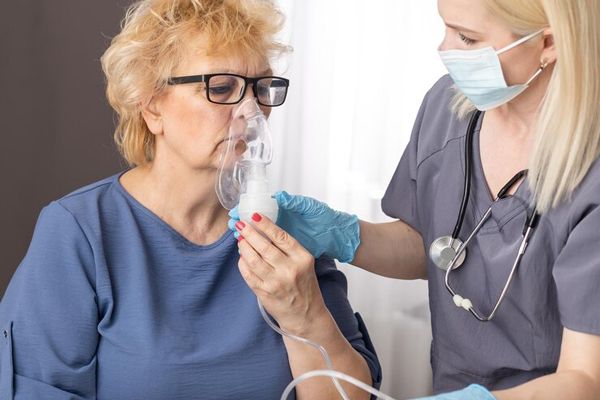 COVID19 - mujer mayor acompañada de un medico mientras se le suministra oxigeno mediante una mascarilla