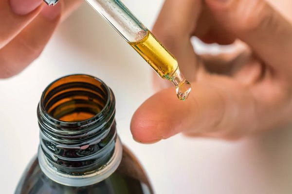 imagen de una mujer con con un frasco de retinoides sosteniendo el cuentagotas de la tapa lleno del medicamento