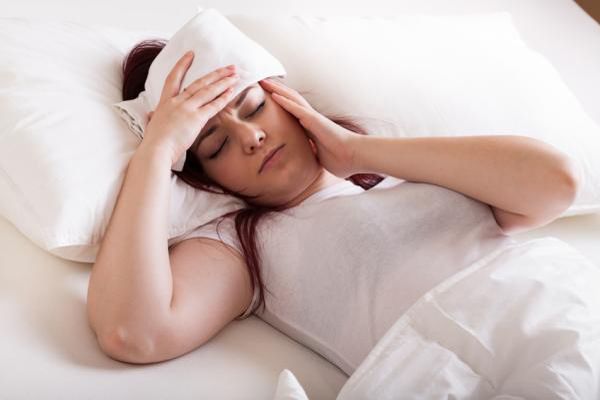 Tuberculosis - mujer tumbada en la cama tapada con un edredón con un pañuelo húmedo sobre la frente para controlar la fiebre