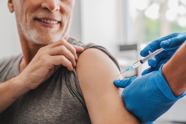 hombre mayor recibiendo la vacuna para el virus en la consulta de su medico