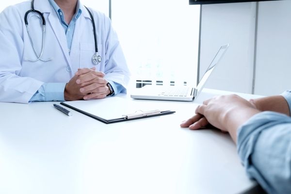 paciente en la consulta del proctólogo explicando cuales son sus problemas en el recto 