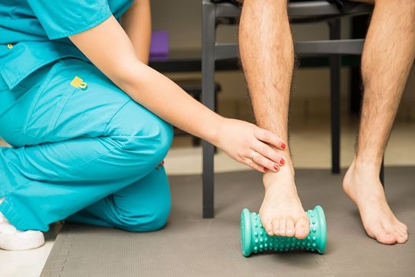 Fascitis plantar - paciente en la consulta del fisioterapeuta haciendo un tratamiento de pisar sobre un rodillo de masaje