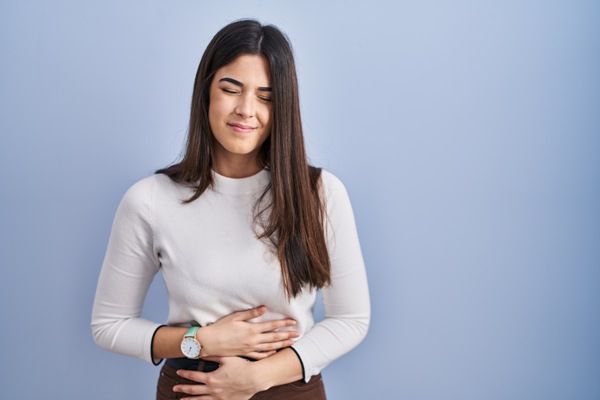 mujer joven agarrándose el vientre por fuertes dolores