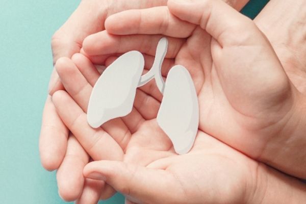Tuberculosis - mujer cogiendo las manos de un niño que tiene entre sus manos un recorte con forma de pulmón