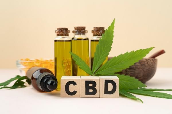 CBD - imagen de unos frascos de productos con CBD sobre una mesa con hojas de marihuana