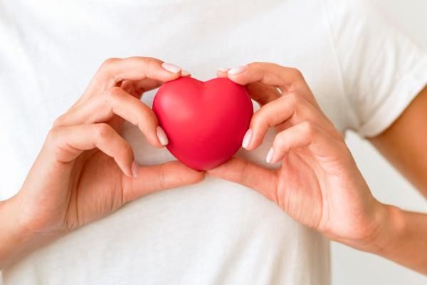 imagen de una mujer sujetando un corazón de juguete con las dos manos sobre su pecho