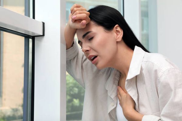 Alergias - Mujer apoyada en el quicio de la ventana con signos evidentes de problemas respiratorios
