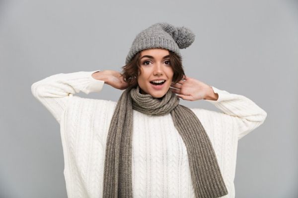 Mujer vestida con un jersey, gorro y bufanda de punto