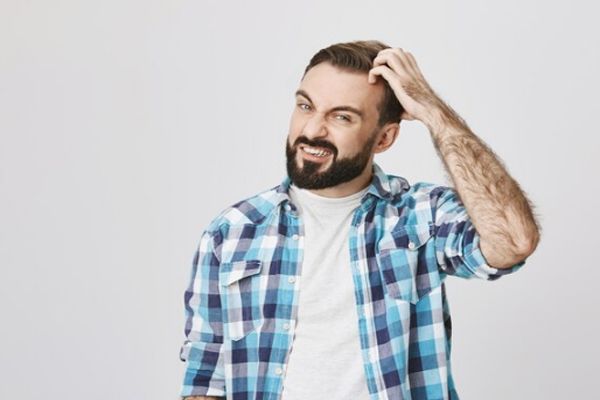 Pediculosis - Hombre con comezón en la cabeza rascándose con la mano