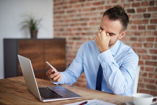 Alopecia por estrés - Hombre estresado en frente al computador con síntomas de alopecia en las entradas
