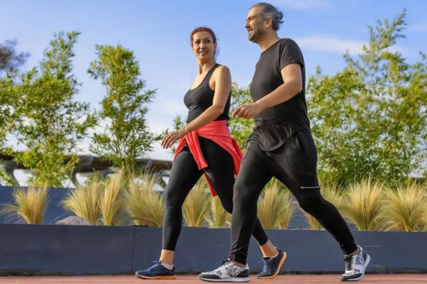 Hombre y mujer adultos paseando para hacer ejercicio y reducir sus niveles de estrés