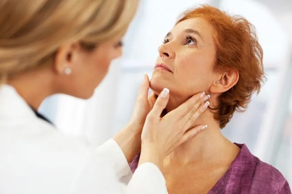 Hipertiroidismo - Endocrina en su consulta palpando el cuello de la paciente buscando signos de la enfermedad