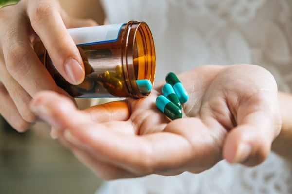 mujer vertiendo pastillas en su manos izquierda