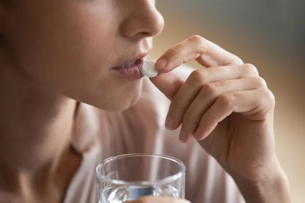 Mujer tomando pastillas para la tiroides 