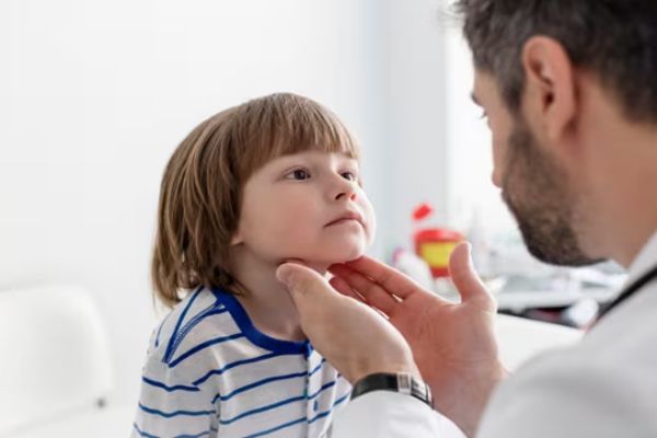 Hipotiroidismo - Especialista examinado la glándula tiroides de un niño en su consulta