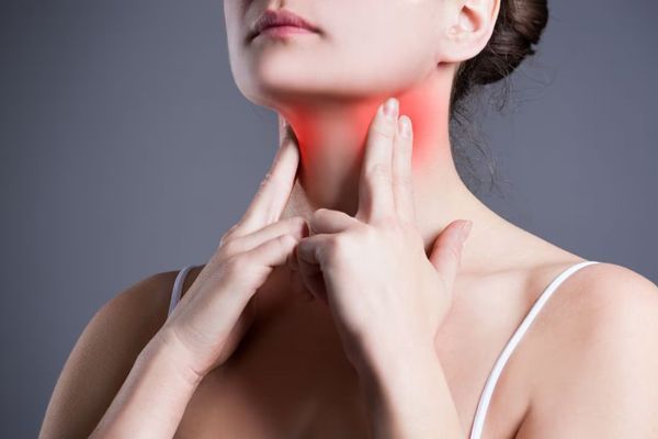Hipertiroidismo - Mujer con masajeando los nódulos tiroideos para aliviar el dolor