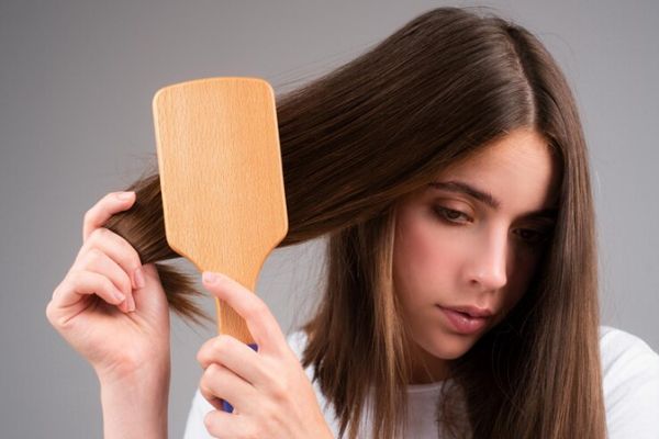 Joven cepillándose su larga melena preocupada por la salud de su cabello 