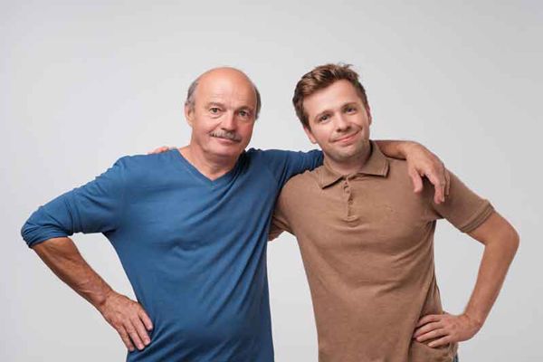 Alopecia - Hombre joven con pelo junto a su padre el cual muestra síntomas graves de alopecia al tener solo el cabello en los laterales de la cabeza