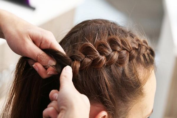 Alopecia - Mujer realizando un peinado tirante en forma de trenza lateral a otra mujer 