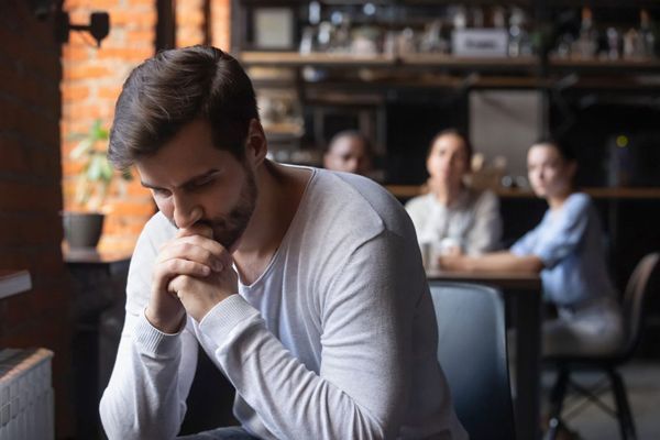 Hiperhidrosis - hombre en un bar apartado de un grupo de personas que lo miran desde otra mesa por culpa del sudor