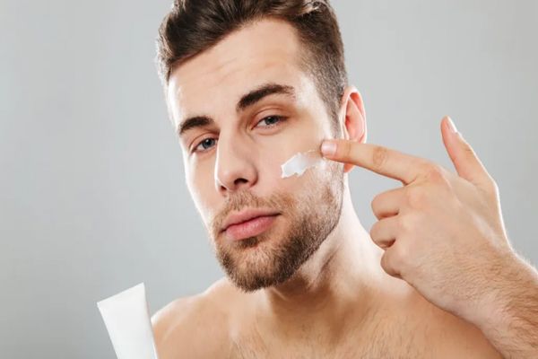 Hombre aplicándose una crema para el cuidado de la piel del rostro
