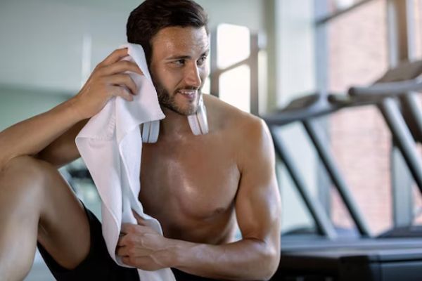 Hiperhidrosis - Hombre adulto secándose el sudor en el gimnasio