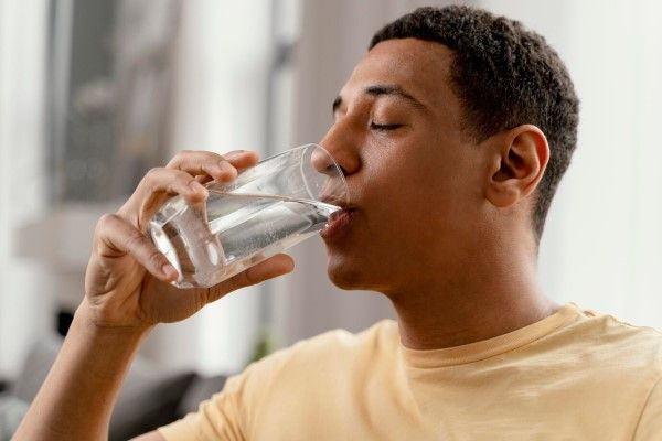 Retrato de hombre en casa bebiendo un vaso de agua