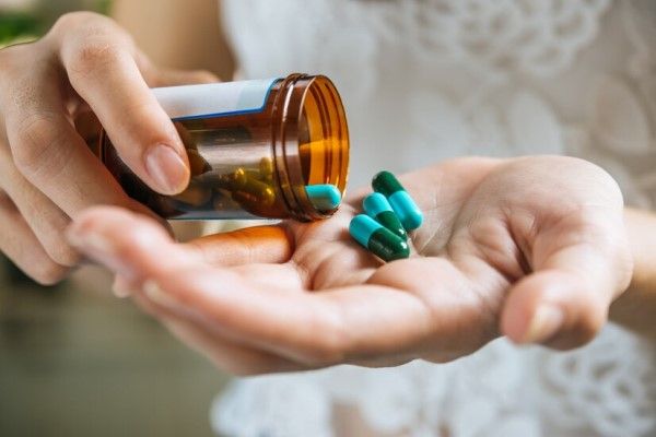 mujer tomando medicamentos istemicos para tratar la enfermedad