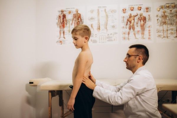 escoliosis - El ortopedista examina a un niño de cerca en la clínica El tratamiento de la escoliosis