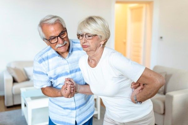 osteonecrosis - Una pareja mayor en casa anciana tiene dolor de espalda y su atractivo esposo la apoya