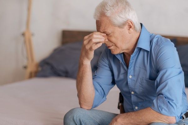 Insuficiencia cardíaca - Hombre anciano sentado en la cama con problemas de fatiga por una insuficiencia cardíaca