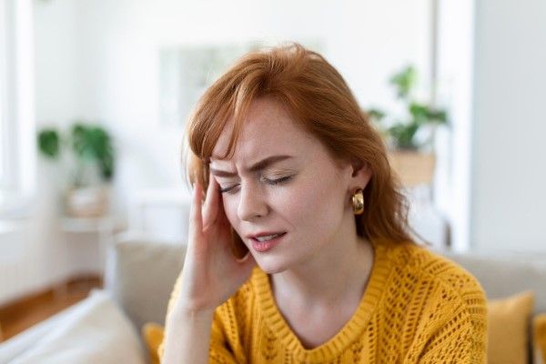 hipertensión - Vista de cerca de la cara fruncida de la mujer que siente un fuerte dolor de cabeza toca la sien para reducir el dolor intenso