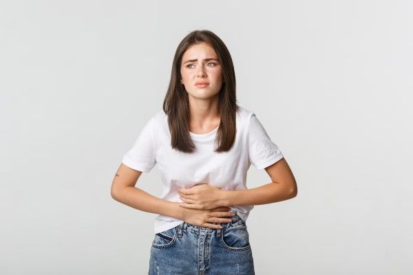 intolerancia al gluten - mujer blanca joven agarrándose el estomago tras haber comido algo con gluten