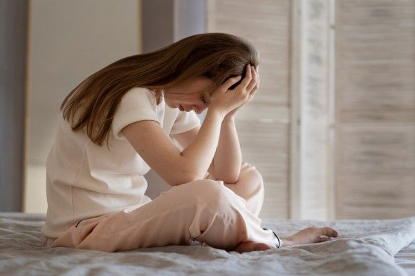 Mujer ansiosa sentada en la cama tiro completo