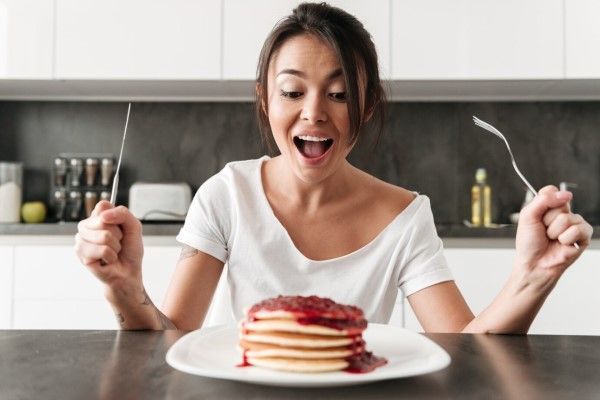Mujer feliz en la cocina a punto de comerse unas tortitas