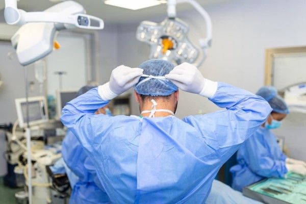 Vista trasera del cirujano masculino con mascarilla quirúrgica en el quirófano del hospital