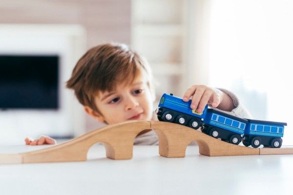 niño con el síndrome jugando contento con un tren, su interés estrecho