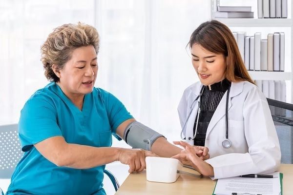 mujer madura en la consulta de su cardióloga que esta tomándole la tensión