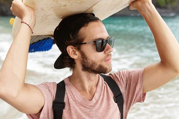 hombre blanco surfista con la tabla de surf en la playa