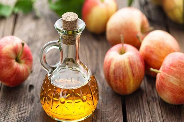 frasco de vinagre de manzana sobre una mesa con manzanas